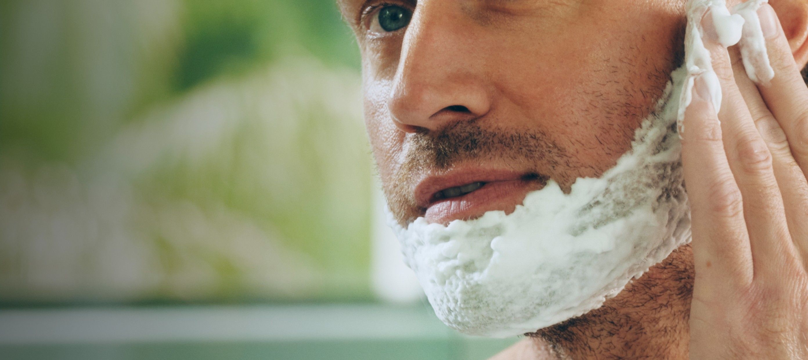 Man applying shave gel to face with hand
