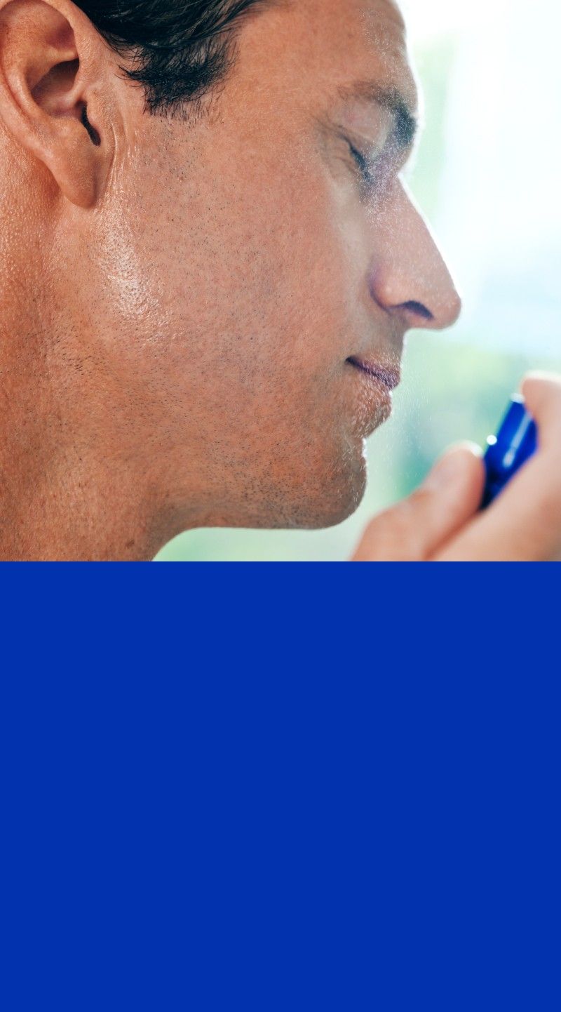 Close-up of a person misting their face with blue bottle.